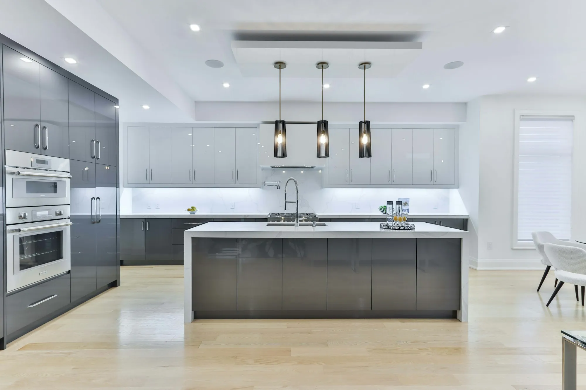 A modern kitchen with grey handleless cabinets, a white island and pendant lights