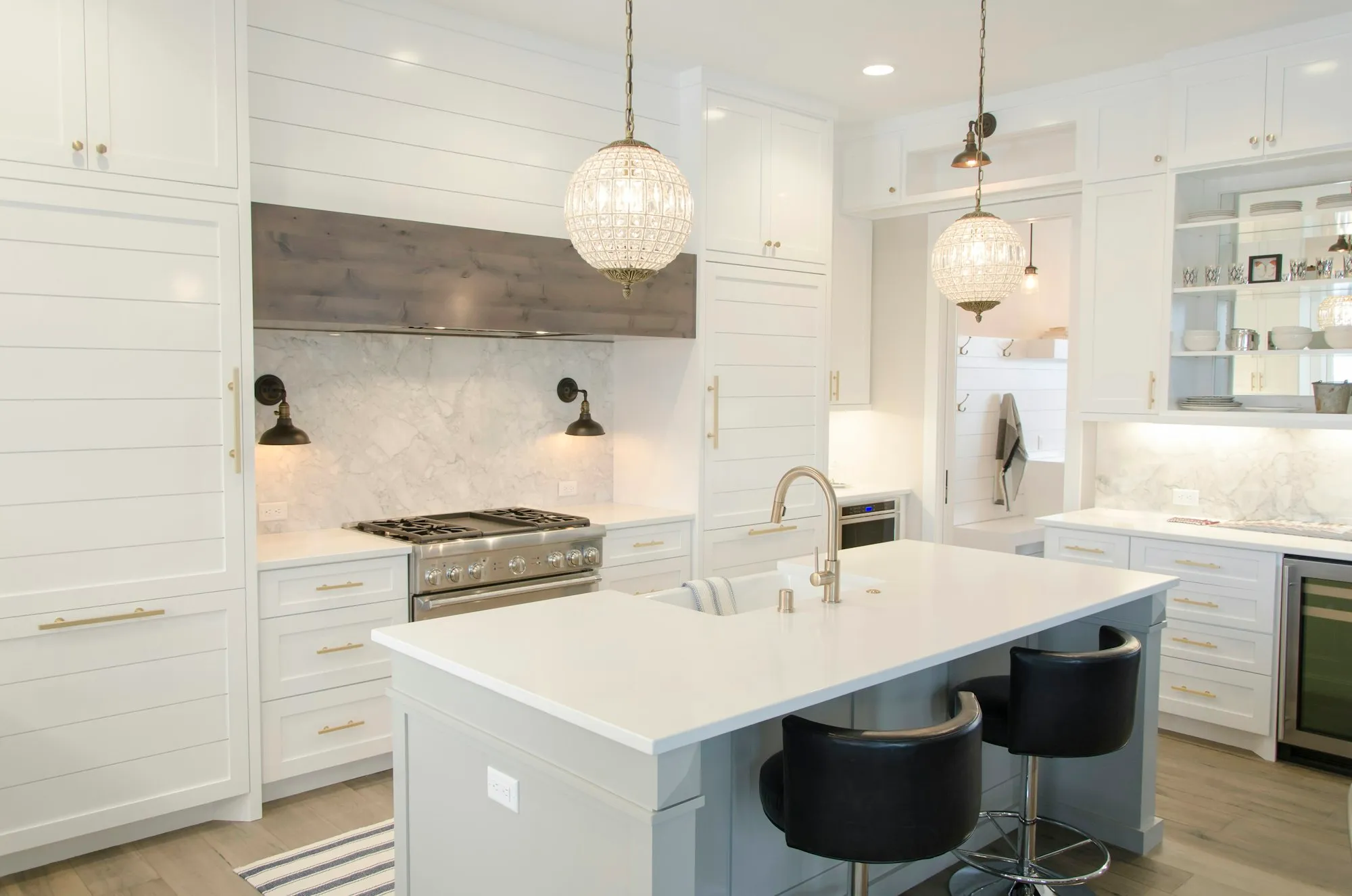 A white shaker style kitchen with brass handles and a stone island