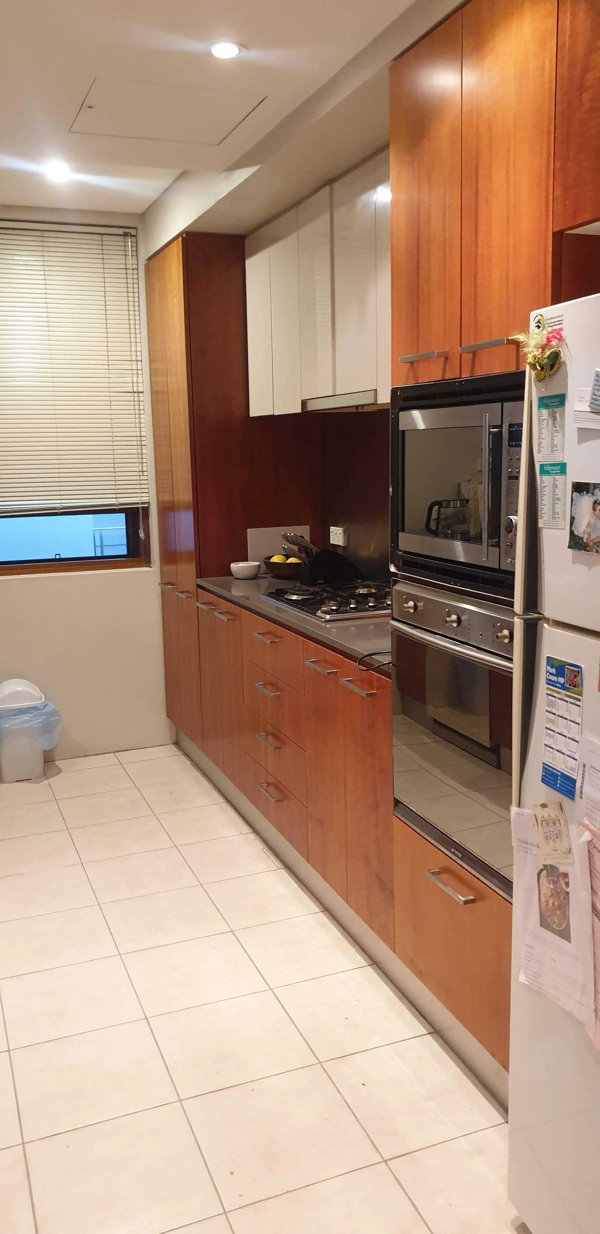 A dated kitchen with dark timber doors and a worn benchtop, before the makeover